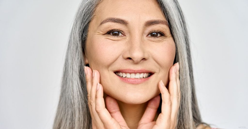 Smiling mature woman with her hands touching her face (model)